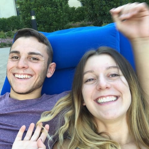 Two smiling people taking a selfie together outdoors