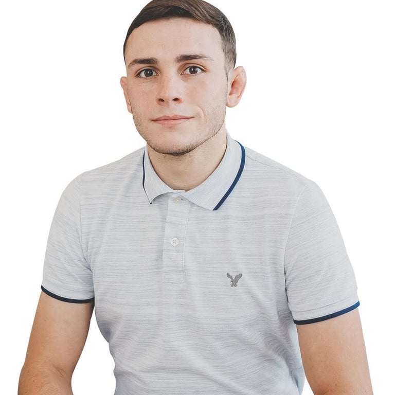 Portrait of a young man wearing a light gray polo shirt with navy trim against a white background